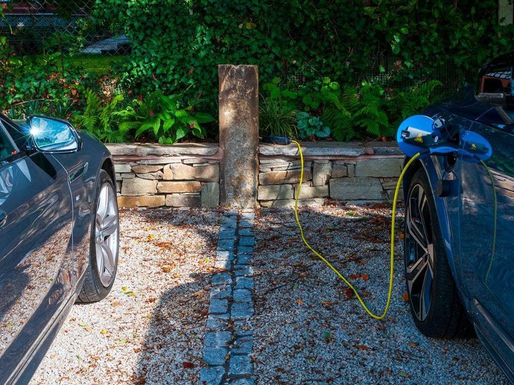 reclaimed sandstone gate post with electric charging point for volvo set within sandstone wall around driveway