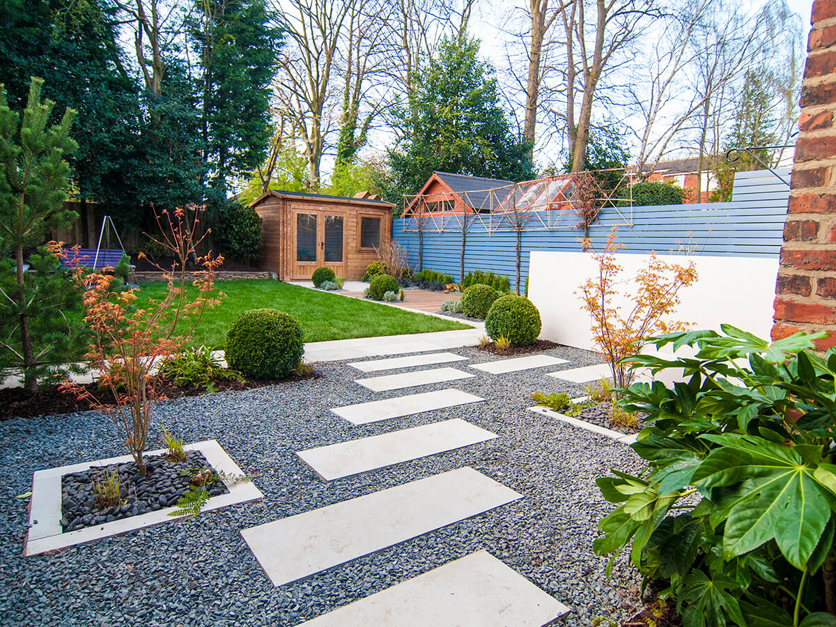 Private residence Heaton Moor view of stepping stones through contemporary Japanese garden with black basalt gravel, acer katsura, fatsia, Chinese black pebbles, box balls, topiary, Little Greene Juniper Ash, pine tree, pleached hornbeam, white rendered wall, dunster summer house.