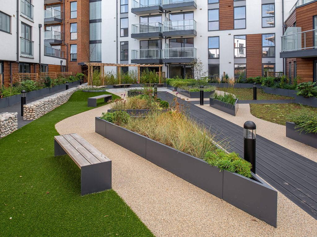 triangluar raised planter on roof garden next to boardwalk and circular pergola with gabion wall and lighting enclosing space