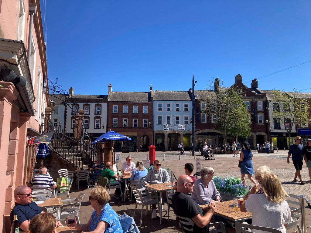 cafe with people sitting in sun on the edge of Carlisle Market Square