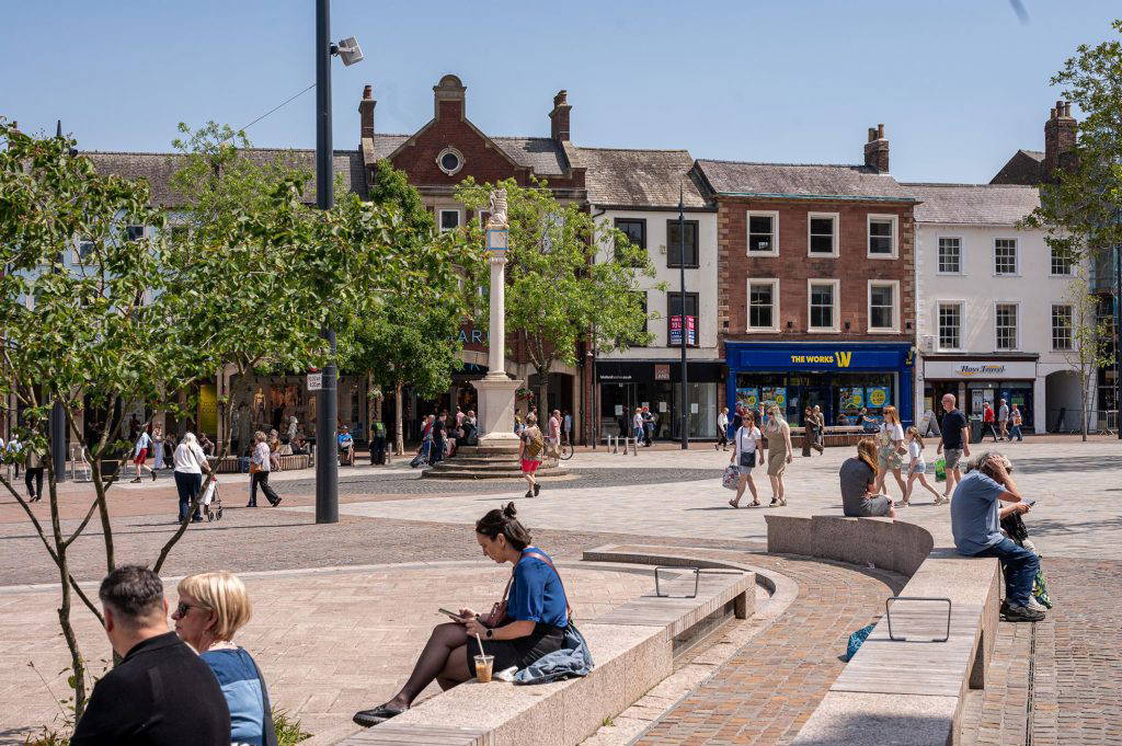 people sitting in Carlisle Market Square in different directions