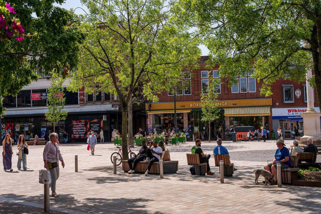 people sitting in Carlisle Market Square in different directions